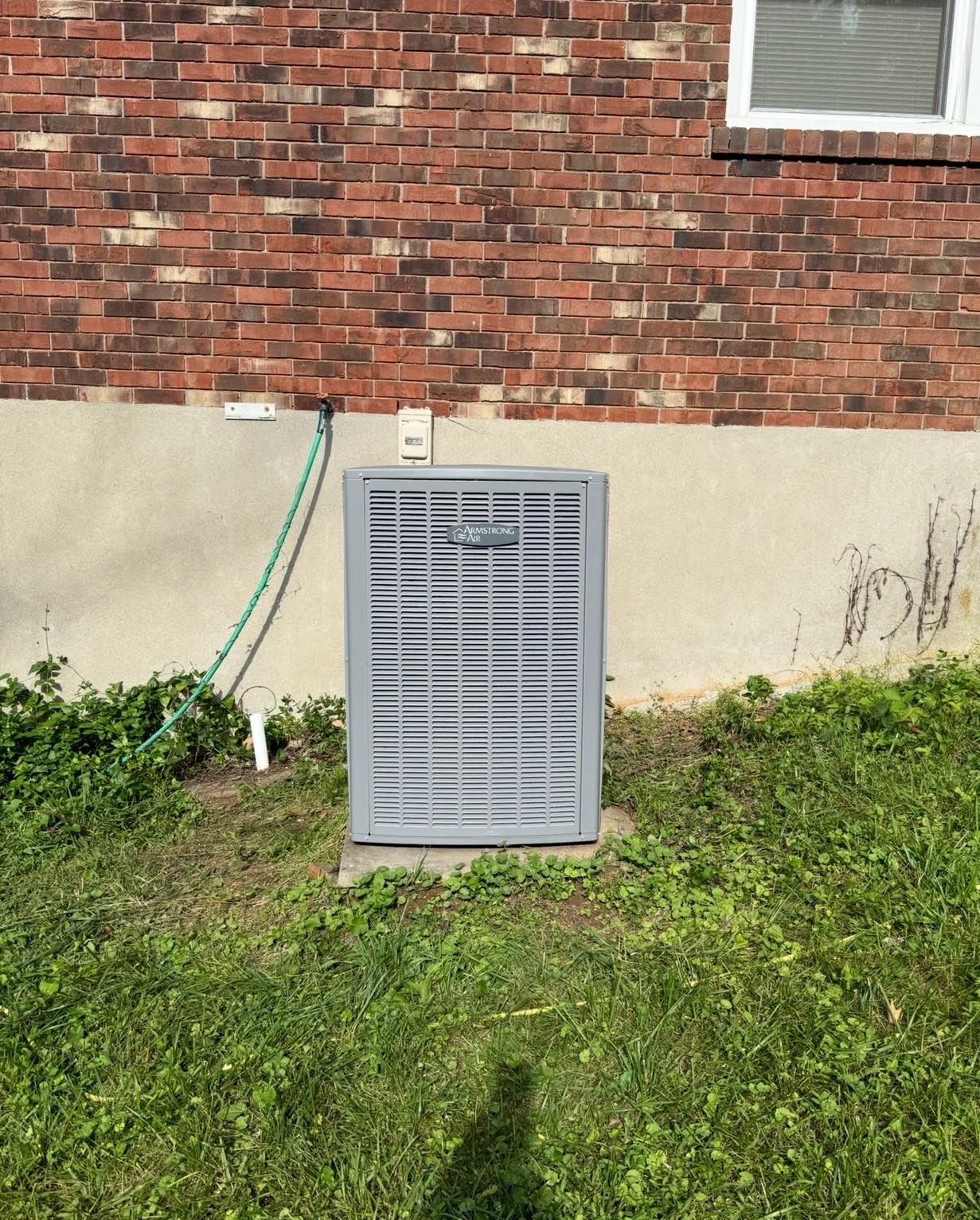 Air conditioner condenser beside a brick home